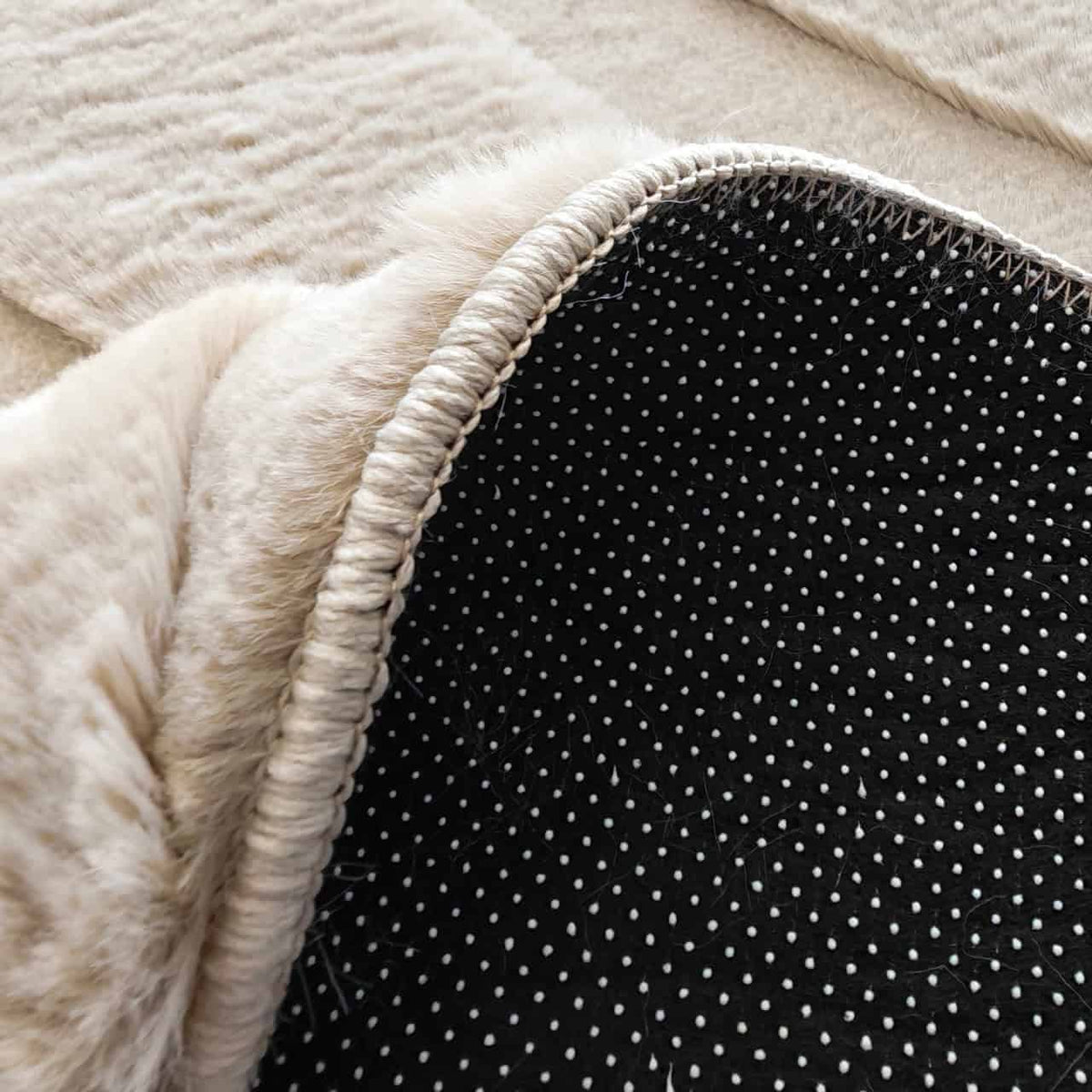 Close-up van het beige vloerkleed Sverre met zwart en witte details.