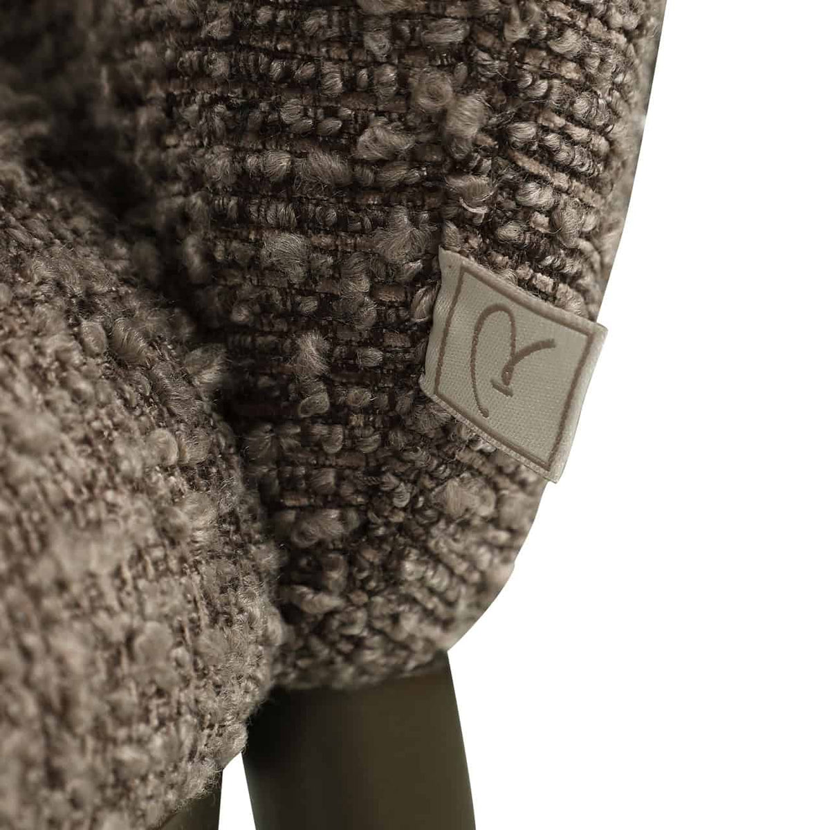Close-up van de Gandy eetkamerstoel met chunky stof en label.