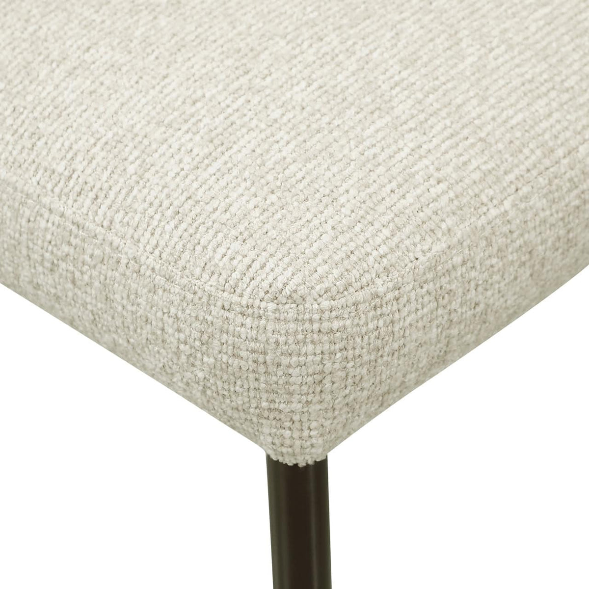 Dichtbijzicht van een beige gestoffeerde eetkamerstoel met zwarte poot.