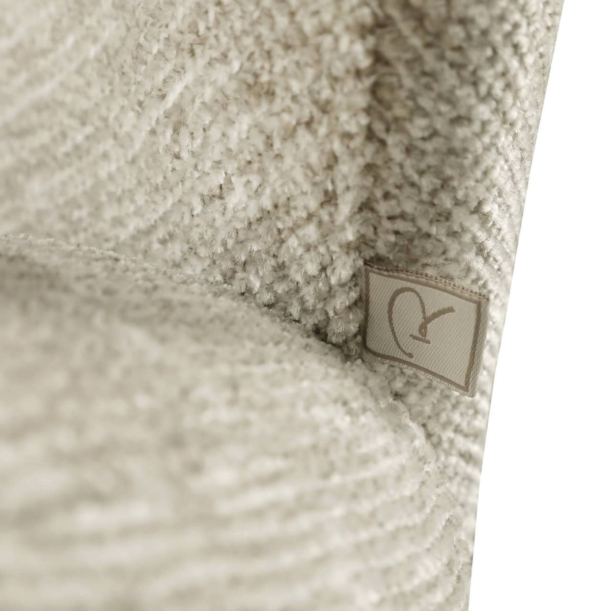 Zacht beige stoffen meubel met textuur en label.